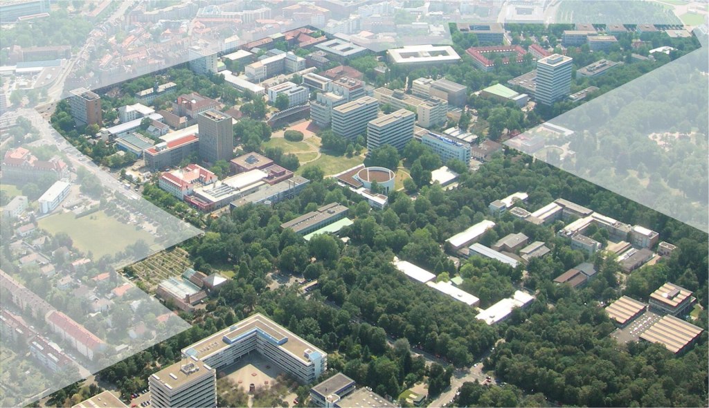 Luftbild vom Campus des Karlsruher Instituts für Technologie: viele Universitätsgebäude und Hochhäuser zwischen grünen Bäumen und Wiesen, ringsum die Stadt.